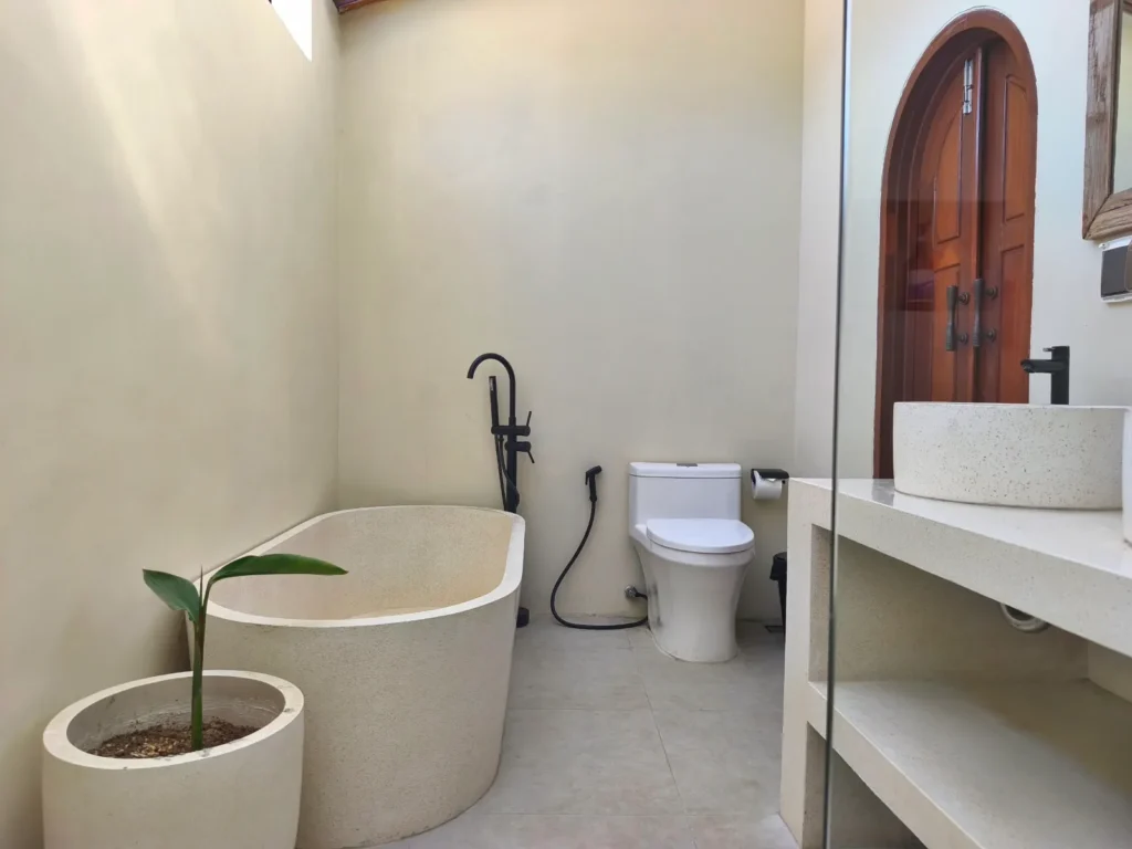 Ensuite bathroom with terrazzo bathtub and walk-in shower in the built villa for sale in Kuta